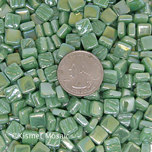 8mm Sea Green mosaic tiles arranged with a quarter for scale, showcasing vibrant colors and iridized finish, ideal for creative projects by artists and DIY enthusiasts.
