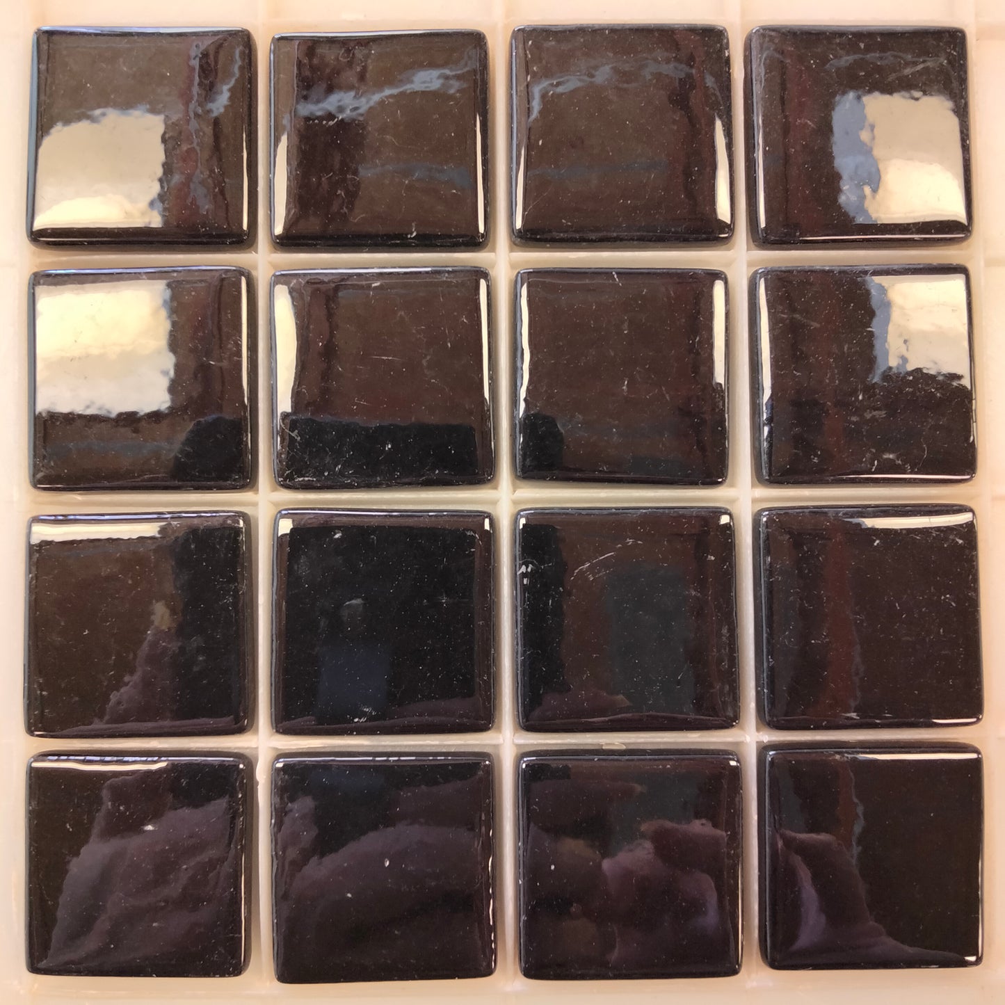 Glossy black porcelain mosaic tiles arranged in a 4x4 grid, suitable for wet or dry environments in artistic and decorative applications.