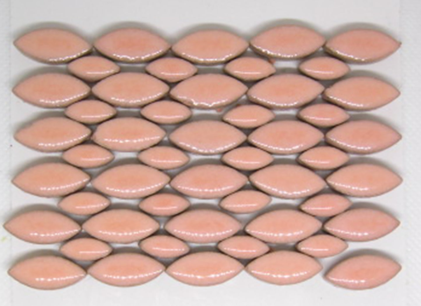 Glazed ceramic mosaic tiles in blush color arranged in a decorative pattern. The tiles feature an elongated petal or leaf shape in two sizes - larger and smaller ellipses. The blush glaze has a soft peachy-pink tone with a glossy, reflective finish. The pattern shows an average number tile in the 2 oz package.