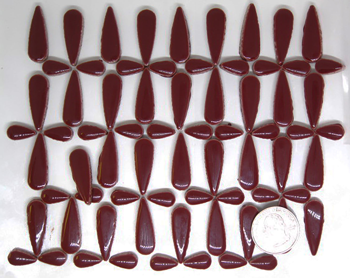 4 ounces of glossy wine red ceramic teardrop tiles arranged in a pattern to showcase product quantity.