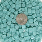 8mm light teal mosaic glass tiles with a quarter for size reference, showcasing vibrant color and glossy finish, ideal for artistic projects.
