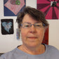 headshot of Kismet Mosaic owner Juanita Canzoneri in front of several of her mosaic art pieces.