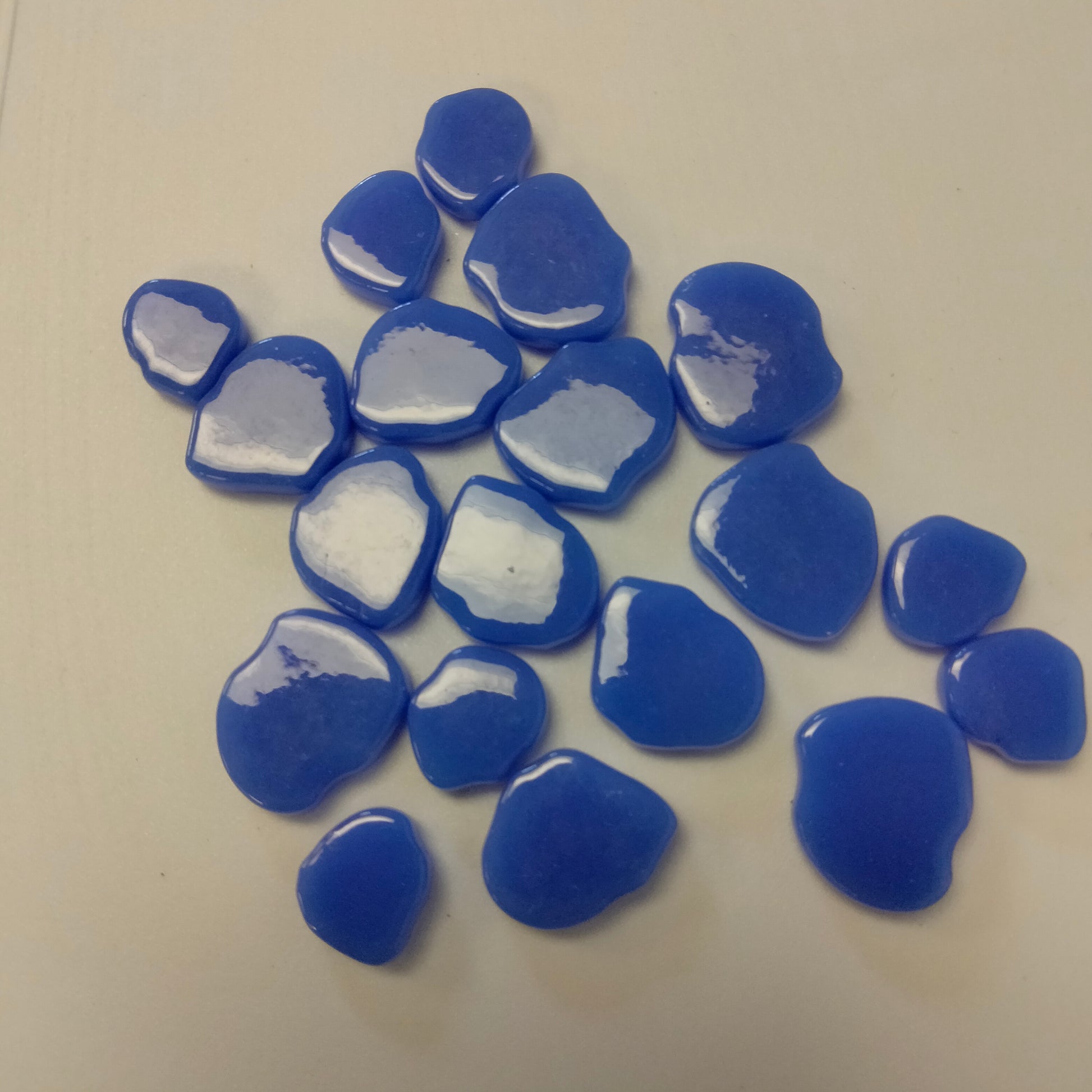 A collection of blue periwinkle glossy mosaic tiles with a petal shape.