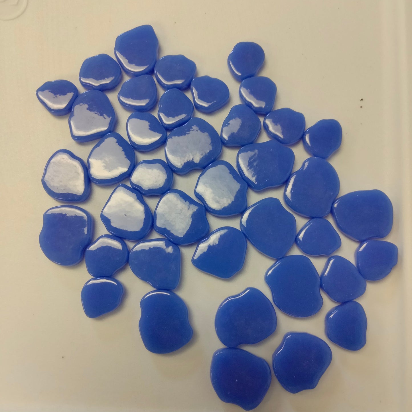A collection of blue periwinkle glossy mosaic tiles with a petal shape.