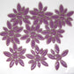 Glazed ceramic petal mosaic tiles in rich purple color arranged in decorative patterns. The tiles feature an elongated petal or ellipse shape in a mix of two sizes - larger oval petals and smaller accent pieces. The deep purple glaze has a glossy, reflective finish that creates beautiful light reflections. This image shows an average tile mix for our 4 ounce quantity.