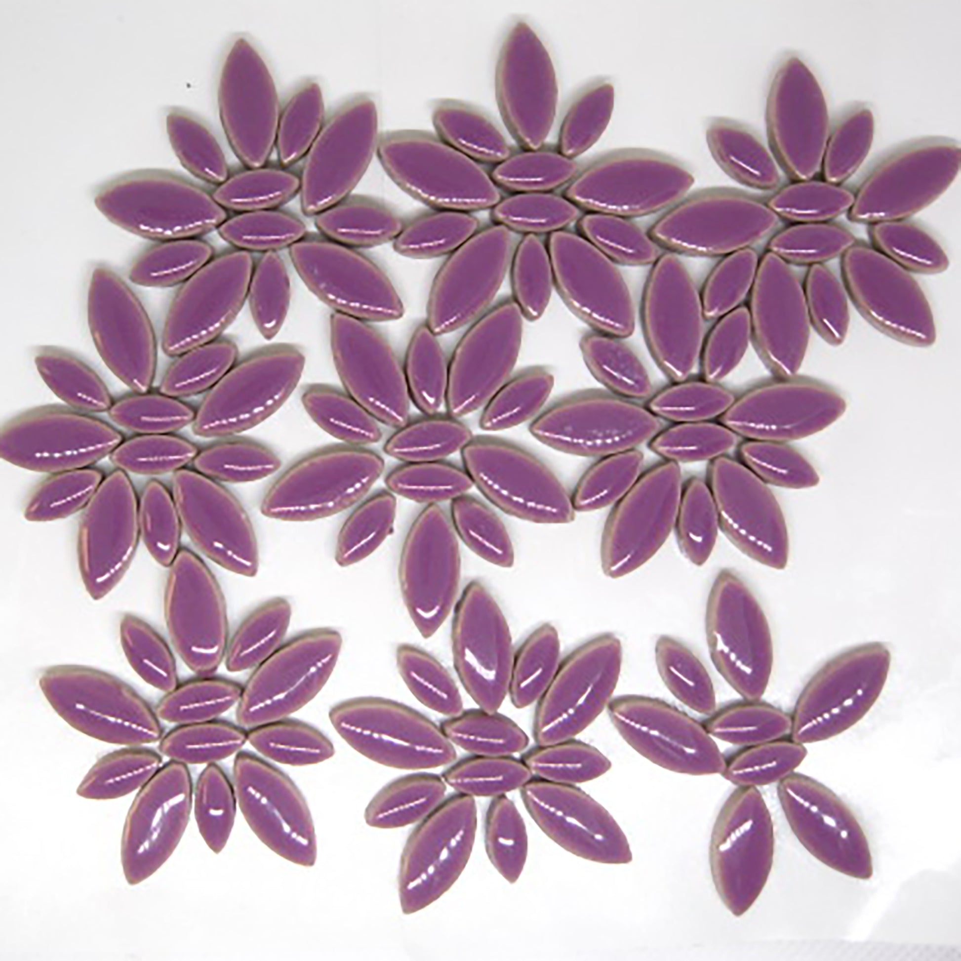 Glazed ceramic petal mosaic tiles in rich purple color arranged in decorative patterns. The tiles feature an elongated petal or ellipse shape in a mix of two sizes - larger oval petals and smaller accent pieces. The deep purple glaze has a glossy, reflective finish that creates beautiful light reflections. This image shows an average tile mix for our 4 ounce quantity.