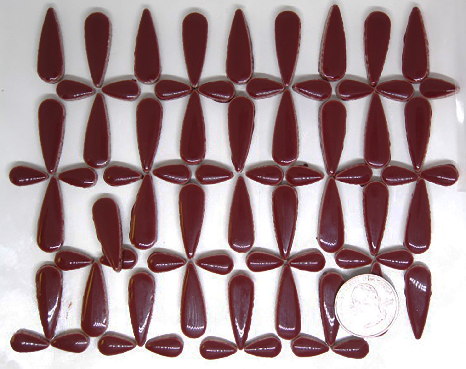 4 ounces of glossy wine red ceramic teardrop tiles arranged in a pattern to showcase product quantity.