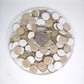 K420 Ivory crystal glass mosaic tiles scattered with quarter coin for size reference showing 5/8 inch round tiles in neutral ivory with a white backing.
