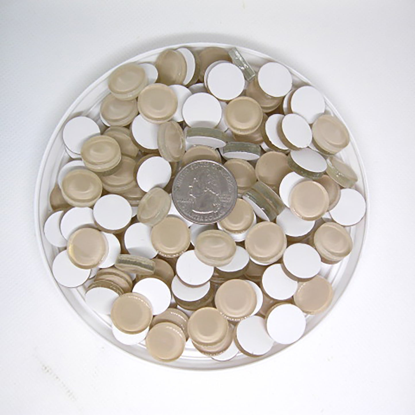 K420 Ivory crystal glass mosaic tiles scattered with quarter coin for size reference showing 5/8 inch round tiles in neutral ivory with a white backing.