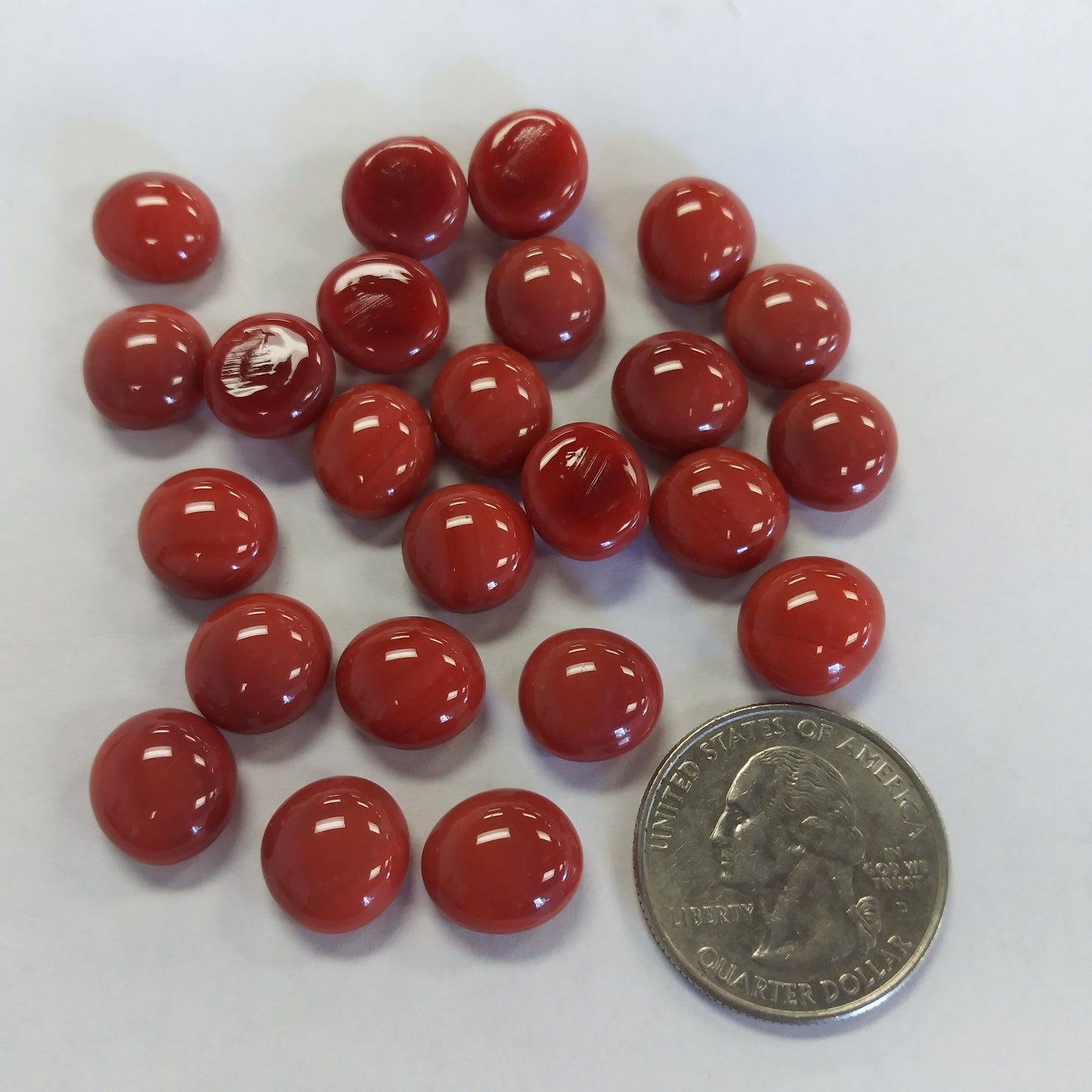 A collection of red glossy mini glass gemstones with a domed surface and flat back, used for mosaics and crafts.
