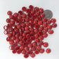 A collection of red glossy mini glass gemstones with a domed surface and flat back, used for mosaics and crafts.