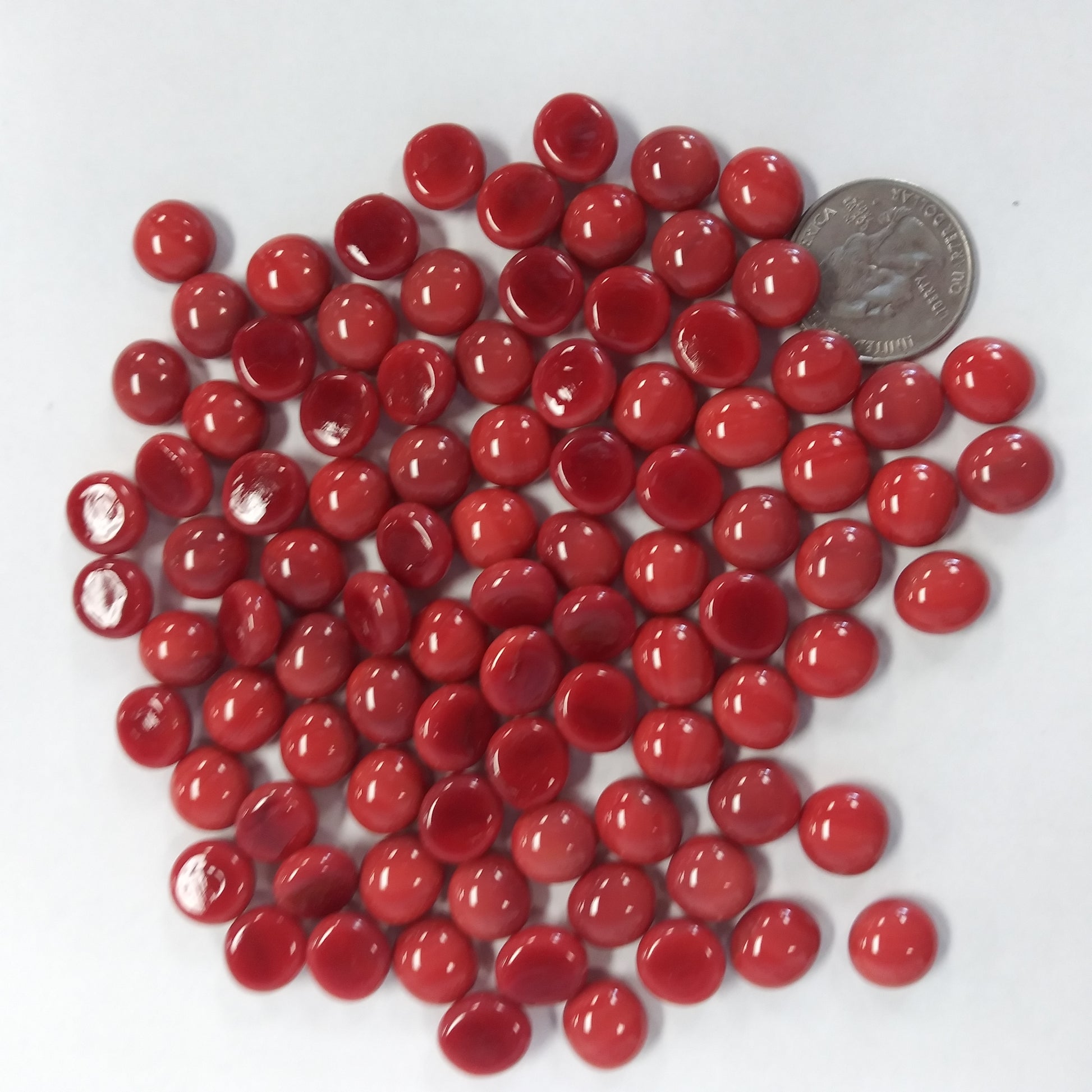 A collection of red glossy mini glass gemstones with a domed surface and flat back, used for mosaics and crafts.